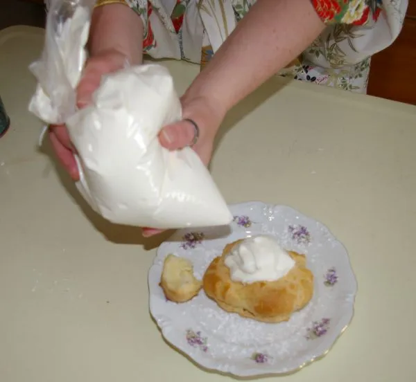 Piping whipped cream into a choux pastry.